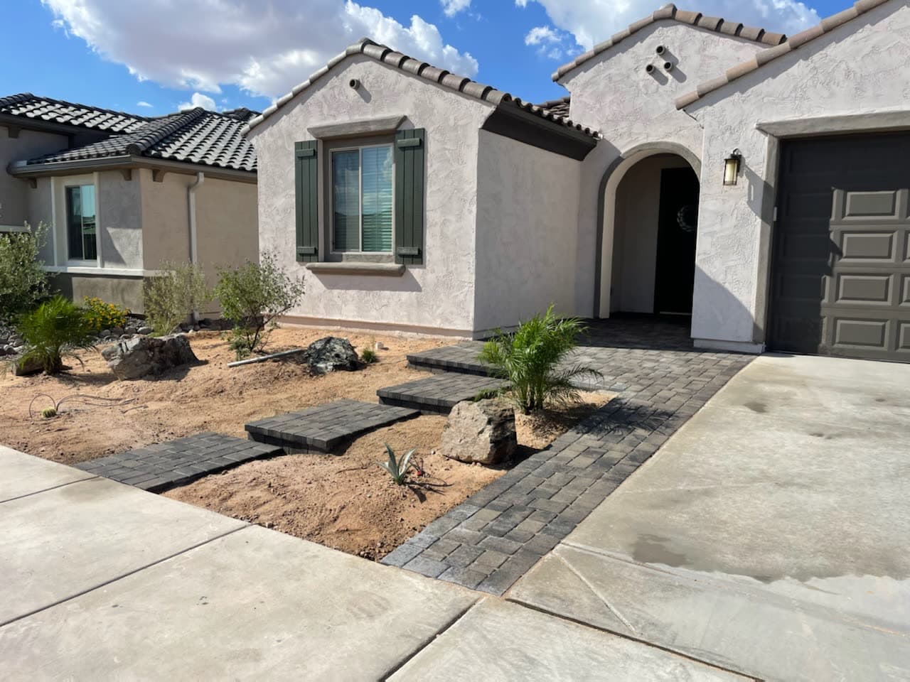A charcoal paver walk and entry steps with boulders and new desert planting
